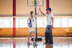 Male coach doing high five with female basketball player