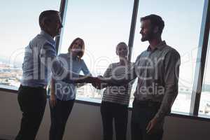 Business people shaking hands against windows at office