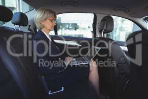 Businesswoman using laptop in car