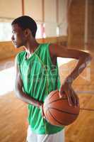 Teenage boy practicing in basketball court