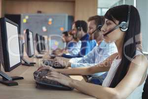 Side view of businesswoman typing on keyboard at call center