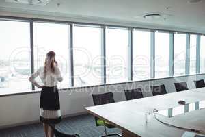 Businesswoman talking on mobile phone in board room