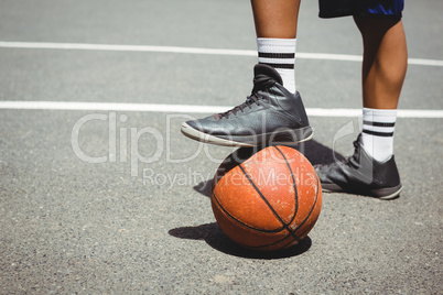 Low section of man standing with one leg on basketball