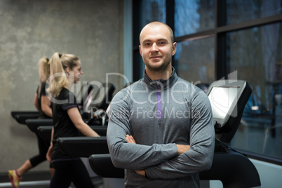 Portrait of man standing with women exercising on treadmills