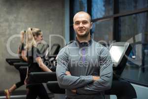 Portrait of man standing with women exercising on treadmills