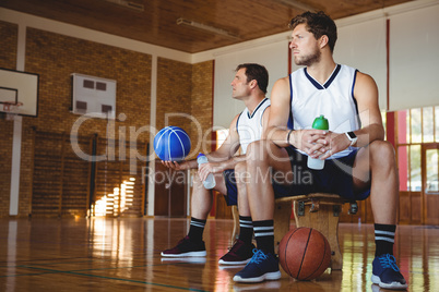 Thoughtful basketball players sitting on bench