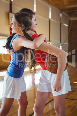 Happy female player embracing in basketball court