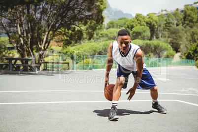 Full length of male teenager practicing basketball