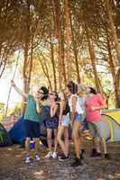 Full length of cheerful friends taking selfie at campsite