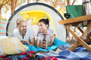 Smiling couple having drink while relaxing tent