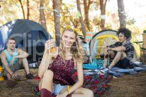 Portrait smiling young woman holding beer glass at campsite
