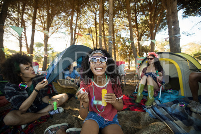 Happy young woman holding bubble wand at campsite