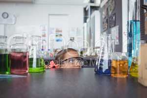 Elementary student hiding behind desk in laboratory