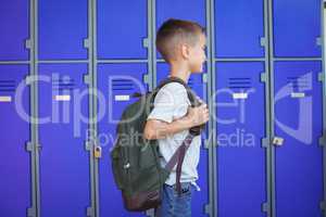 Side view of boy carrying backpack against lockers