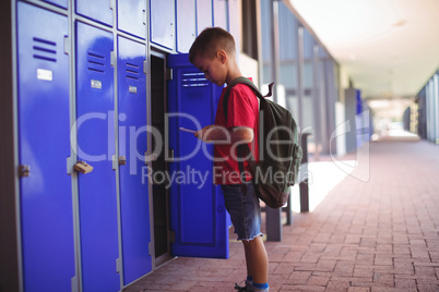 Boy using mobile phone by open locker