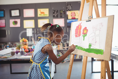 Side view of concentrated girl painting on canvas