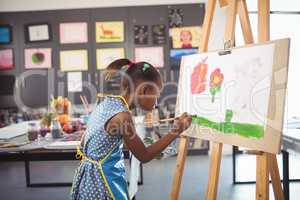 Side view of concentrated girl painting on canvas