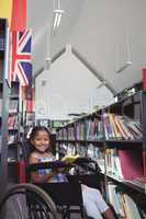 Smiling girl with book on wheelchair in library