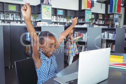 Girl with arms raised looking in laptop