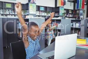 Girl with arms raised looking in laptop