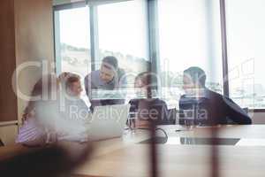Business people discussing in board room seen through glass