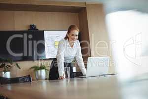 Portrait of businesswoman leaning by laptop on desk