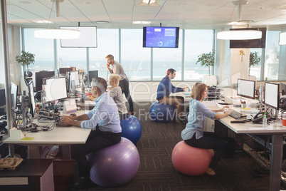 Business people working at desk while sitting on exercise balls