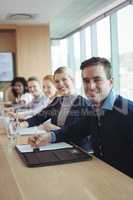 Portrait of smiling businessman with colleagues sitting at office