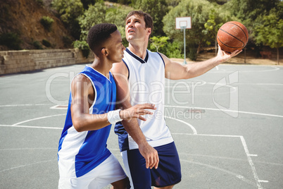 Players playing basketball on sunny day