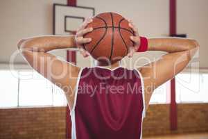 Rear view of basketball player with ball in court
