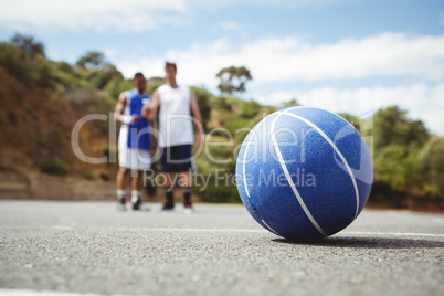 Blue basketball on ground with player standing in background