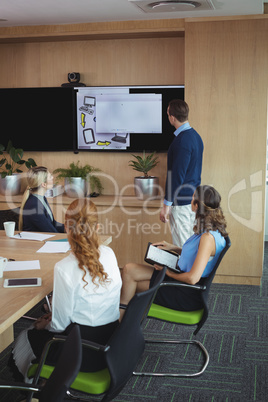 Business people looking at device screen during meeting