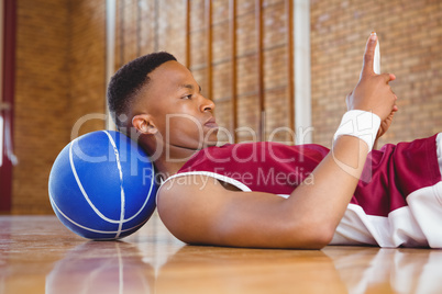 Side view of male basketball player using mobile phone