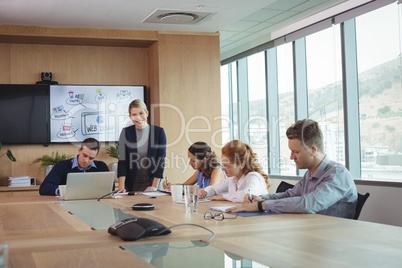 Smiling businesswoman with team working at conference table