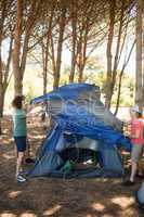 Full length of friends making tent