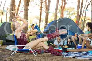 Woman sitting on chair with friends at campsite