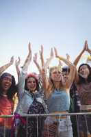 Cheerful female fans against clear sky enjoying music festival