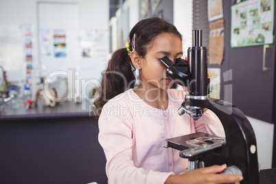 Elementary schoolgirl using microscope at laboratory