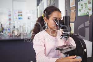 Elementary schoolgirl using microscope at laboratory