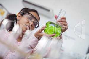 Elementary student holding green chemical in beaker at laboratory