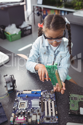 Elementary girl assembling circuit board on desk