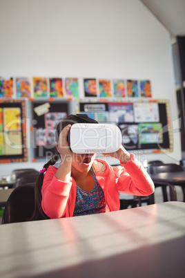 Surprised girl using virtual reality glasses in classroom