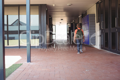 Full length of boy with backpack walking in corridor