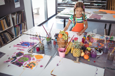 High angle view of concentrated girl painting at desk