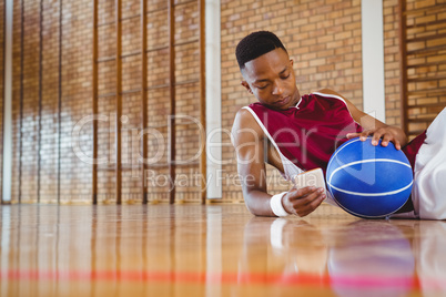 Male basketball player using mobile phone