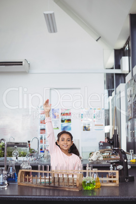 Portrait of smiling elementary student with hands raised at science laboratory
