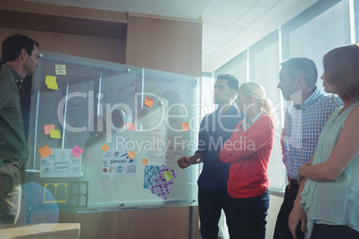 Business people discussing by whiteboard at office