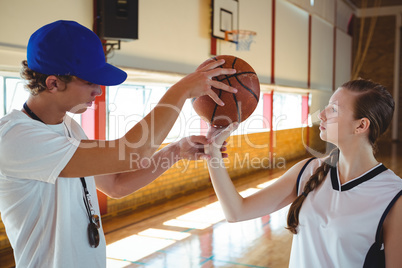 Male coach training female basketball player