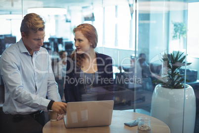 Young businesswoman with male colleague working on laptop