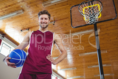 Male basketball player standing by basketball hoop